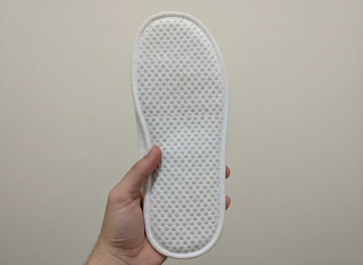 The dotted non-slip sole of a terry hotel slipper held up to the camera
